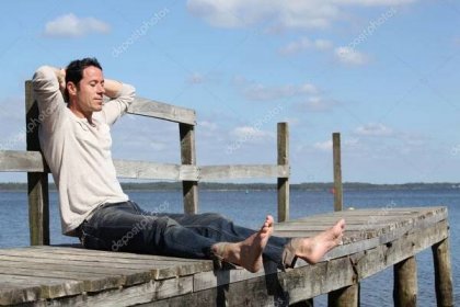 Stáhnout - Bosý muž seděl na dřevěné molo na sluníčku — Stock obrázek