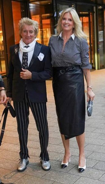 a man in a suit and tie stands next to a woman in a black skirt