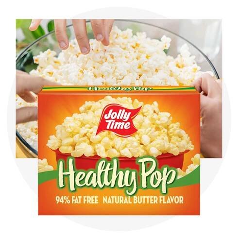 Three hands reaching into a bowl of popcorn with a carton of Healthy Pop Popcorn in front