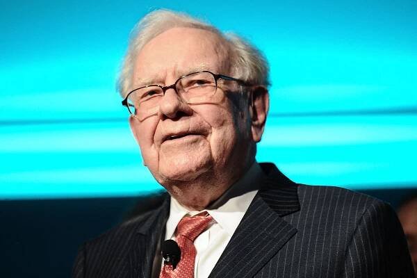 Warren Buffett attending an event smiling slightly
