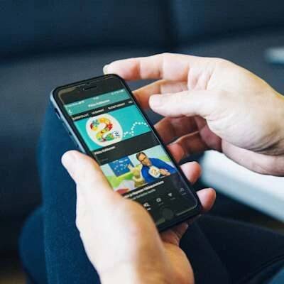 A person browses Yle Areena on a smartphone, screen visible in the image.