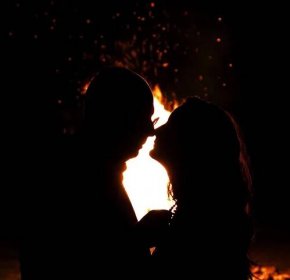 Portrét krásné mladé dvojice líbat před požárem v noci — Stock fotografie