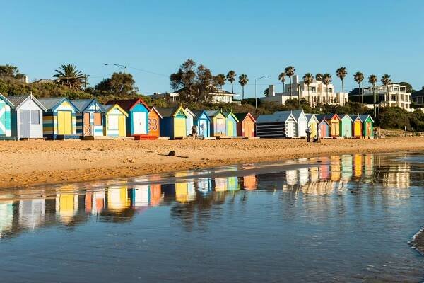 Colorful beach huts reflected in the water at Brighton Beach, Port Phillip Bay.