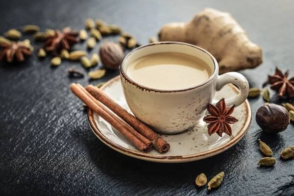 a cup of coffee with cinnamon and star anise next to it on a saucer