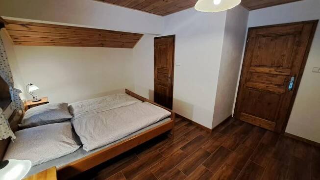 a bedroom with a bed and a wooden floor at Chalupa u Uhříků in Rajnochovice