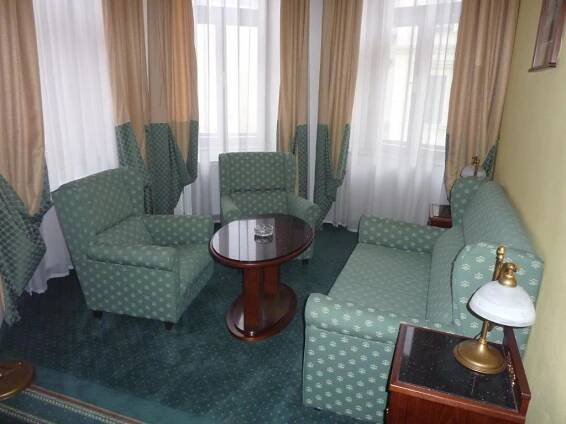 a living room with green chairs and a table and a table at Grandhotel Garni in Jihlava