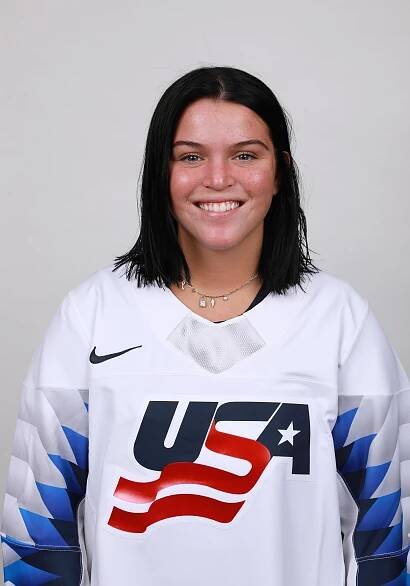 Person smiling in a white 'USA' sports jersey with a grey background.