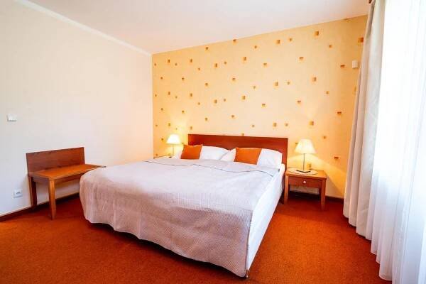 a bedroom with a large white bed and two lamps at Golf Hotel Austerlitz in Slavkov u Brna