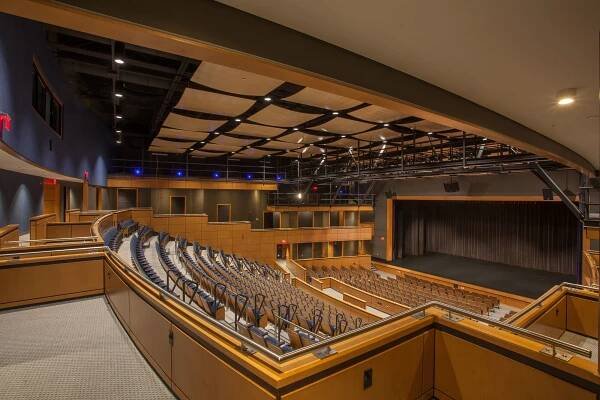 View of the auditorium with warm wooden tones and dark blue accents. 