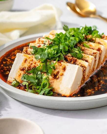 Up close with silken tofu on a plate garnished.