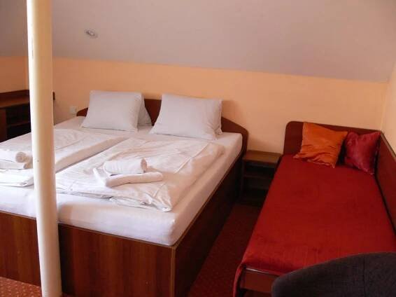a bedroom with a bed with white sheets at Penzion Oaza in Luhačovice