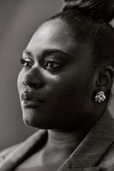 A close-up black-and-white portrait shows Danielle Brooks somewhat in profile from the neck up looking serious but composed. 