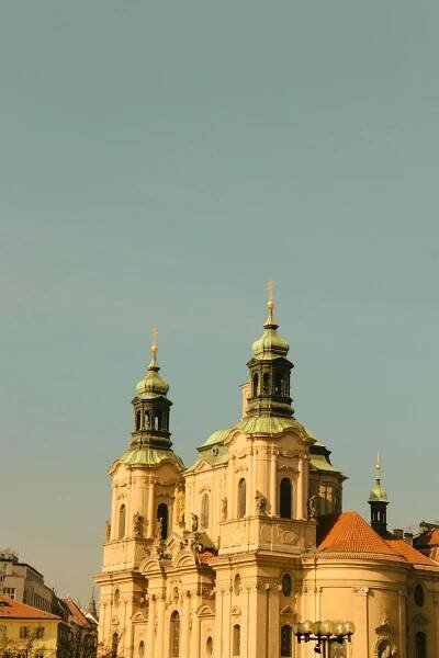 bezplatná Podmanivý západ slunce na kostel sv. Mikuláše v Praze, zachycující jeho historickou krásu. Základová fotografie
