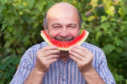 zralý kavkazský muž s knírem jíst šťavnatý vodní meloun s potěšením a úsměvem. - adult eating fruit - stock snímky, obrázky a fotky