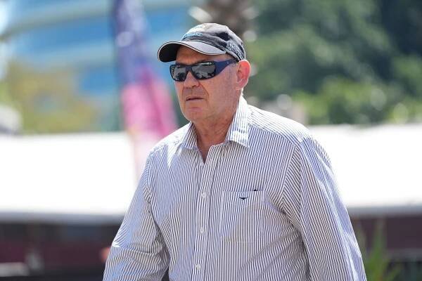 A man wearing sunglasses and a cap, walking towards court.