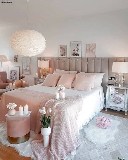 a white bedroom with pink bedding and decor on the walls, along with candles