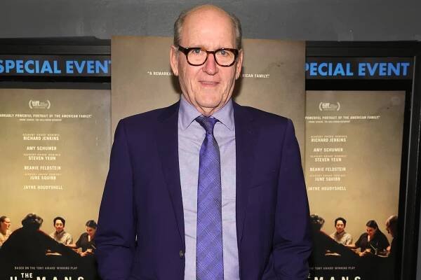 Richard Jenkins standing in a suit with a purple tie.