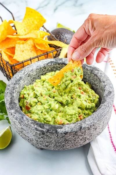 A picture of someone dipping a chip in the finished recipe.
