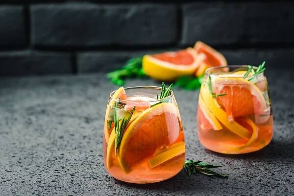 Grapefruit mocktail in a cute highball glass garnished with slices of grapefruit and rosemary
