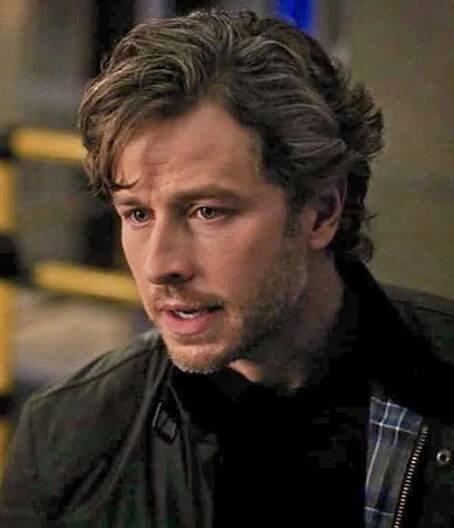 a close up of a person wearing a jacket and looking to the side with a serious look on his face