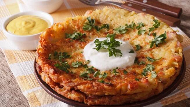 A close-up of Rosti with sauce and parsley on a plate on the table. 
