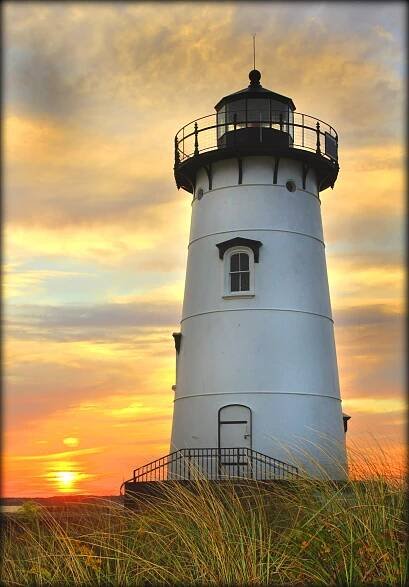 A white lighthouse in front of an orange sunset