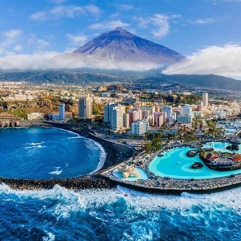 an aerial view of a city with a volcano in the background