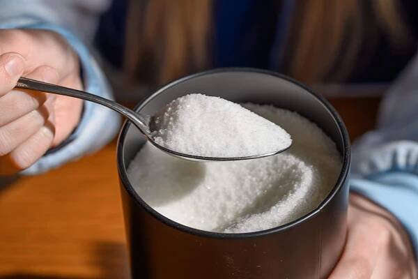 powdered white sweetener in metal container being spooned out
