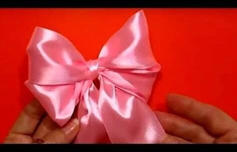 someone is holding a pink bow in their hand