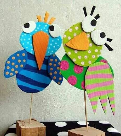 two colorful paper birds sitting on top of wooden blocks