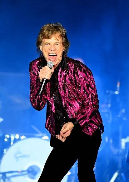 a man in a pink jacket singing into a microphone
