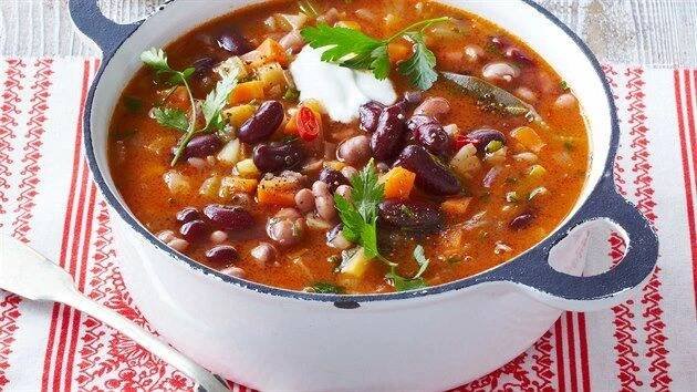 a white bowl filled with beans and vegetables on top of a red and white napkin