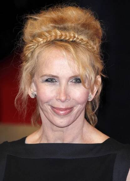 At the 2010 BAFTA Awards in London, Trudie Styler stuns in a black gown with a dramatic neckline, her look elevated by a braided updo and sculpted volume—every detail exuding classic red carpet elegance.