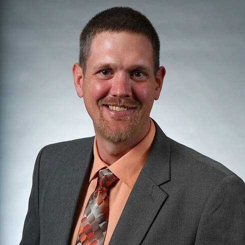 A man in a suit and tie is smiling for the camera
