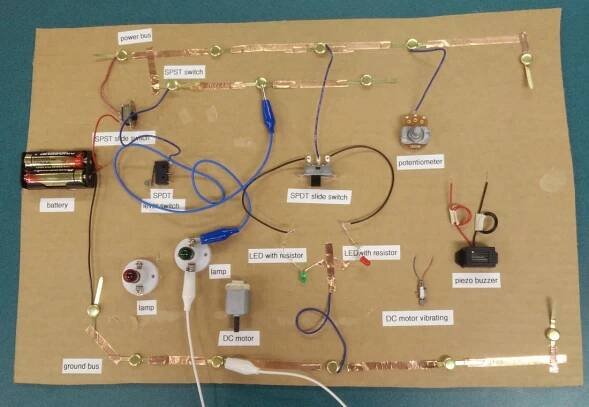 Demonstration board, wires and LED lights and battery pack, all labeled on a cardboard backing