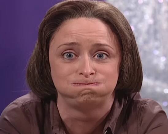 Rachel Dratch puffs up her lips and jaw as though she's suppressing something.