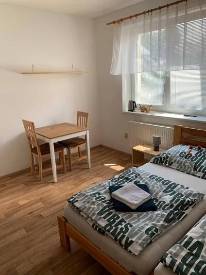 a bedroom with a bed and a dining room table at Penzion Na Potoce in Ledeč nad Sázavou