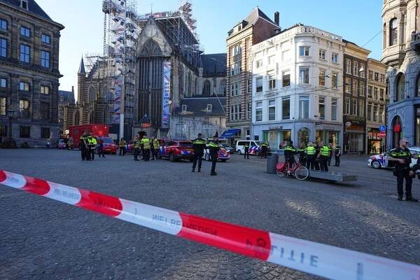 Police officers stand behind a cordoned off area after a stabbing near Dam Square in central Amsterdam