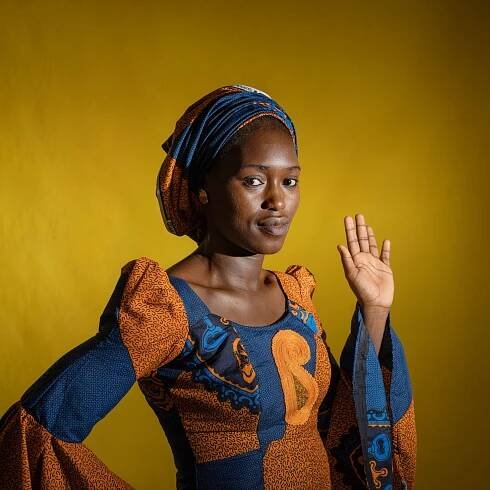 a woman holding her hand up and standing for a portrait