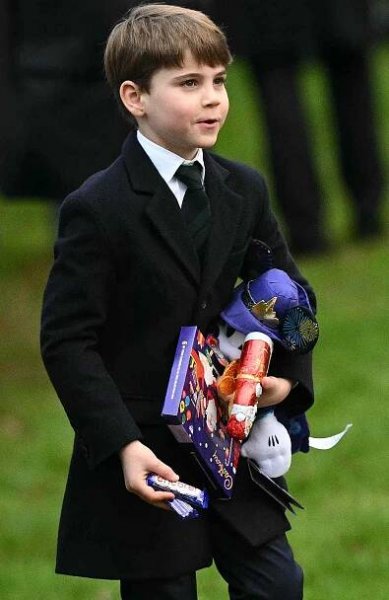 Britain's Prince Louis of Wales reacts as he carries gifts from wellwishers, after attending the Royal Family's traditional Christmas Day service at St Mary Magdalene Church in Sandringham