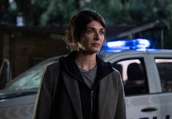 Soledad Villamil as Ema stands in the dark in front of a police car in an image from ‘Caught.’