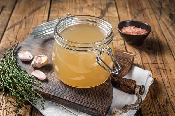 Bone broth chicken soup glass jar wooden background top view (1)