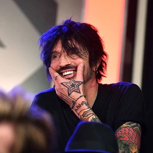 Tommy Lee smiles in a black shirt during a press conference.