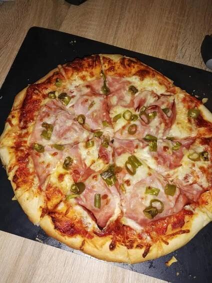 a pizza sitting on top of a cutting board covered in cheese and meat toppings