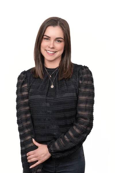 A woman in black shirt and necklace smiling for the camera.