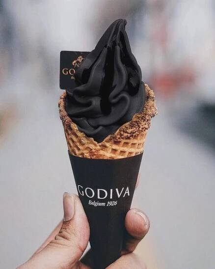 a hand holding an ice cream cone with chocolate topping