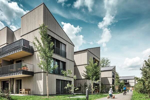 Udržitelné dřevěné bytové domy s prostornými balkony a klidnou přírodní atmosférou pro moderní bydlení.