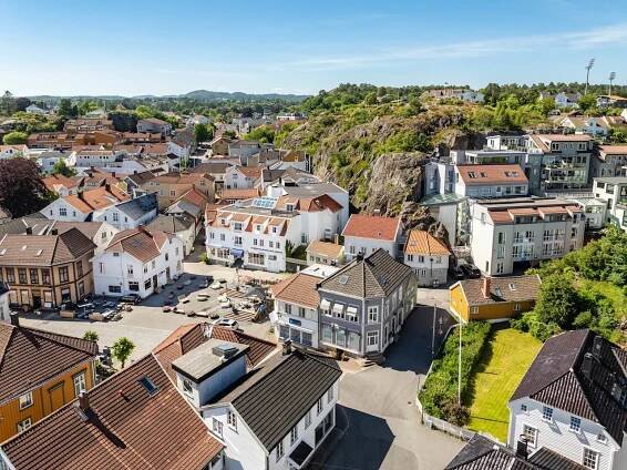 Aerial view of a European town with tightly-packed houses and buildings, nestled amongst greenery and rocky hills.