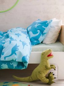 Povlečení JÄTTELIK s motivy dinosaurů na dětské posteli, vedle postele je plyšový dinosaurus.