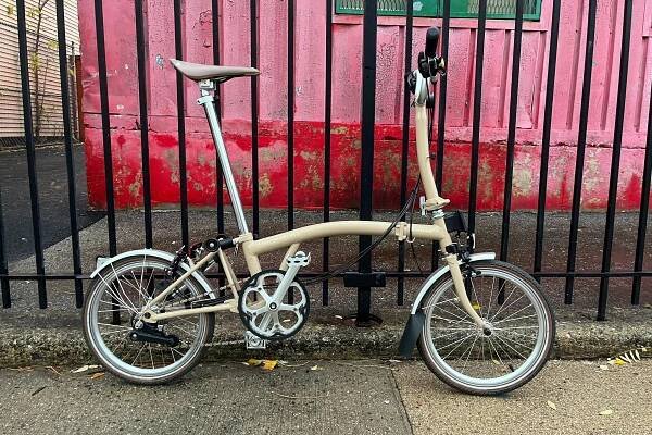 a brompton c line explore bike next to a fence